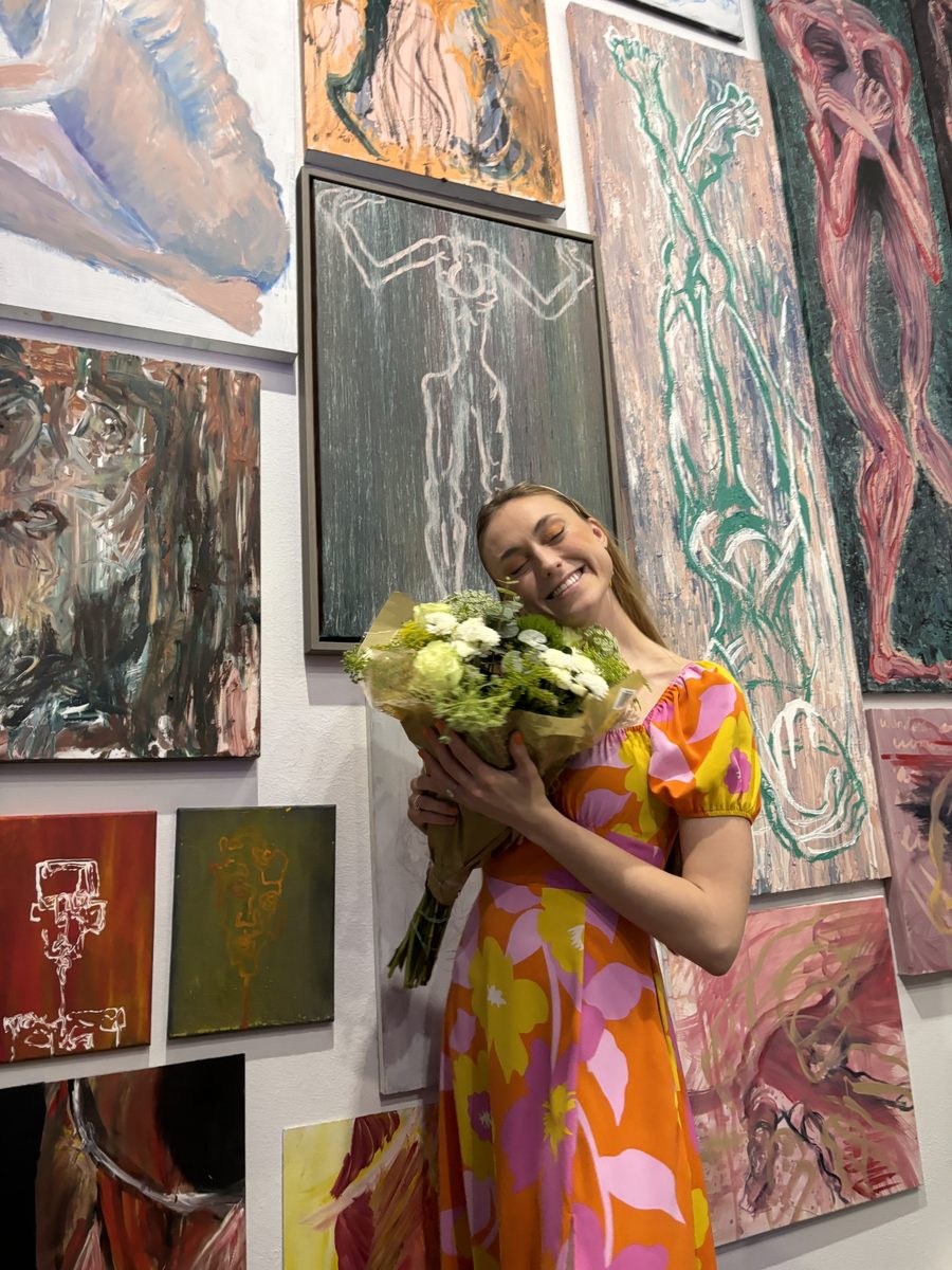 Lilly O'Brien posing in front of her art in a gallery