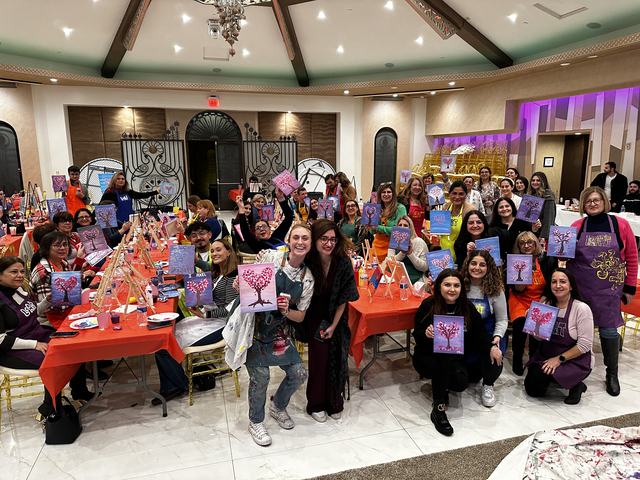 A full room of guests holding their finished paintings